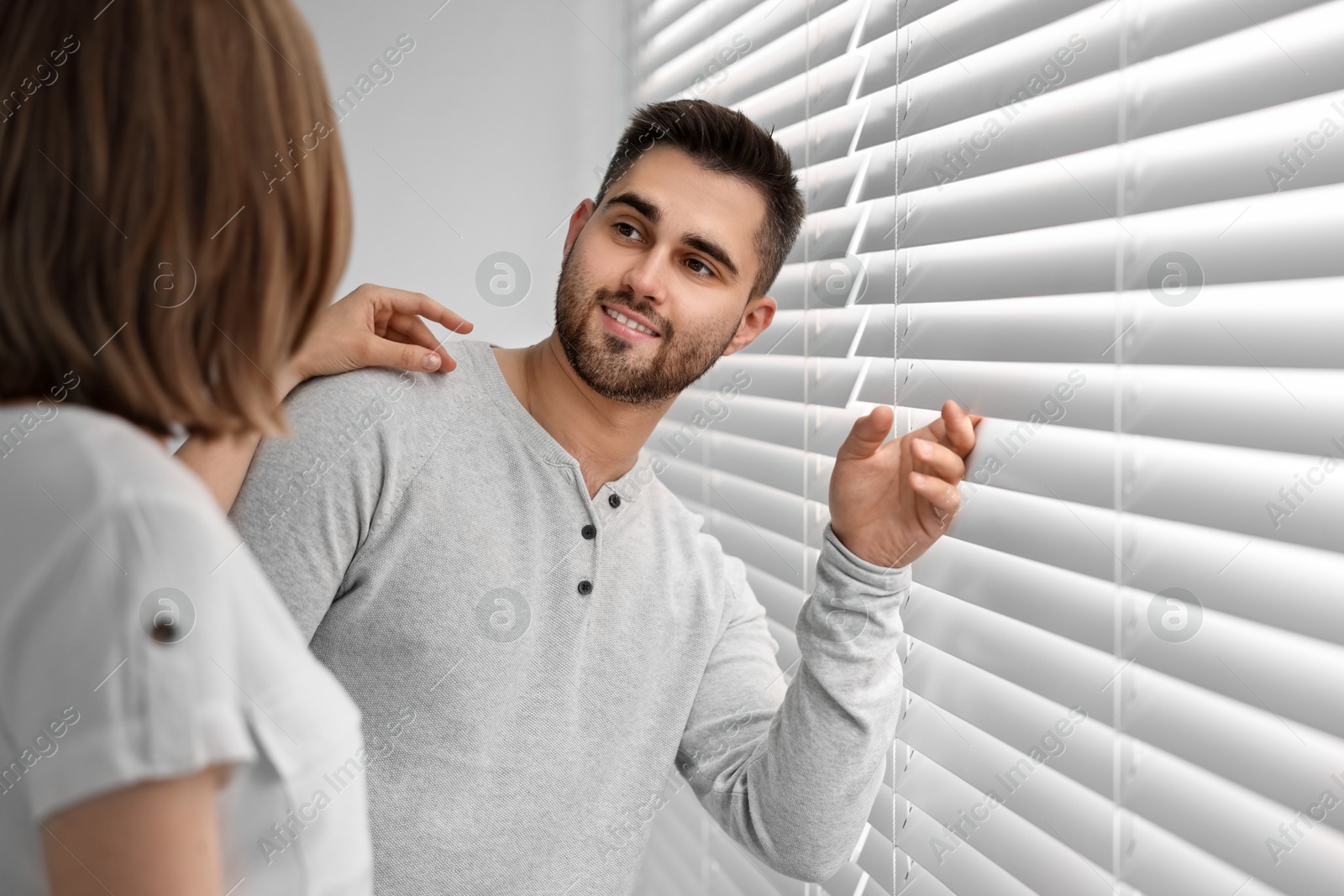 Photo of Young couple near window blinds at home