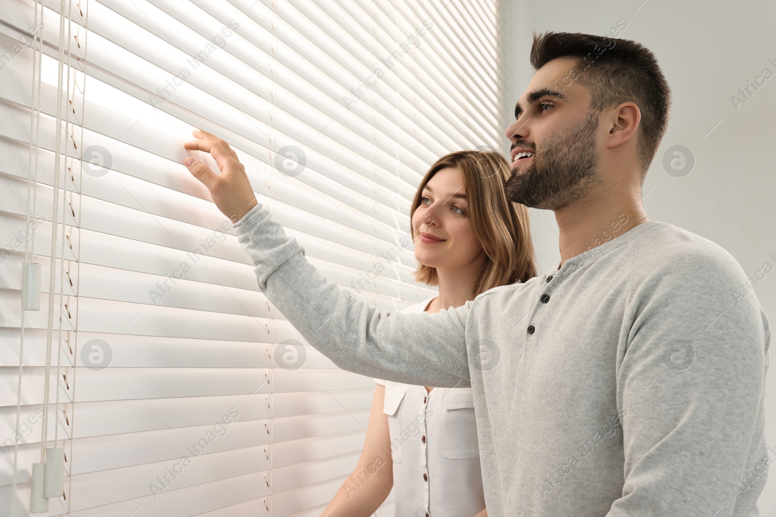 Photo of Young couple near window blinds at home