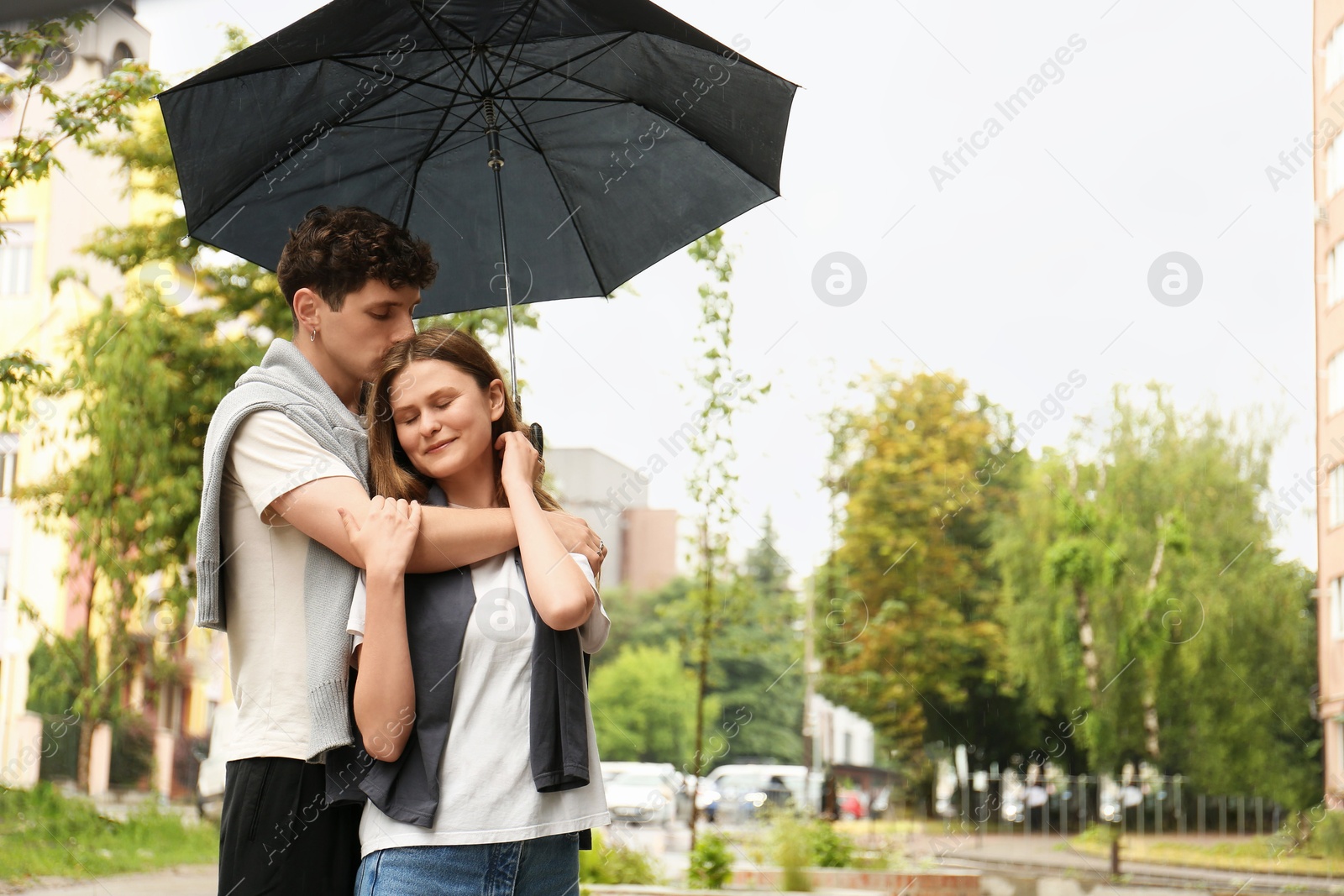 Photo of International dating. Lovely young couple with umbrella spending time together outdoors, space for text