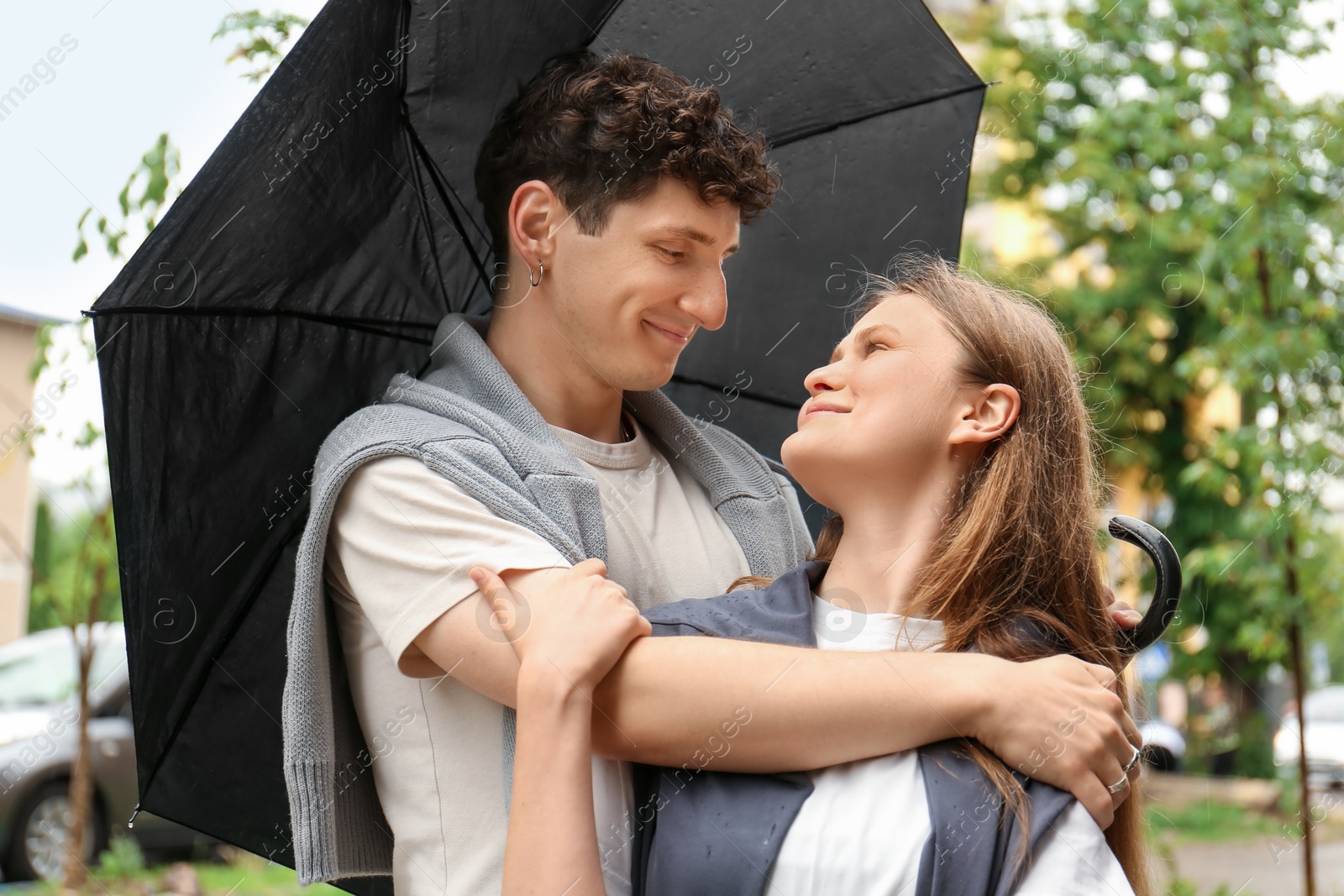 Photo of International dating. Lovely young couple with umbrella spending time together outdoors