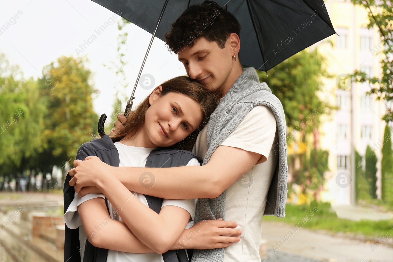 Photo of International dating. Lovely young couple with umbrella spending time together outdoors