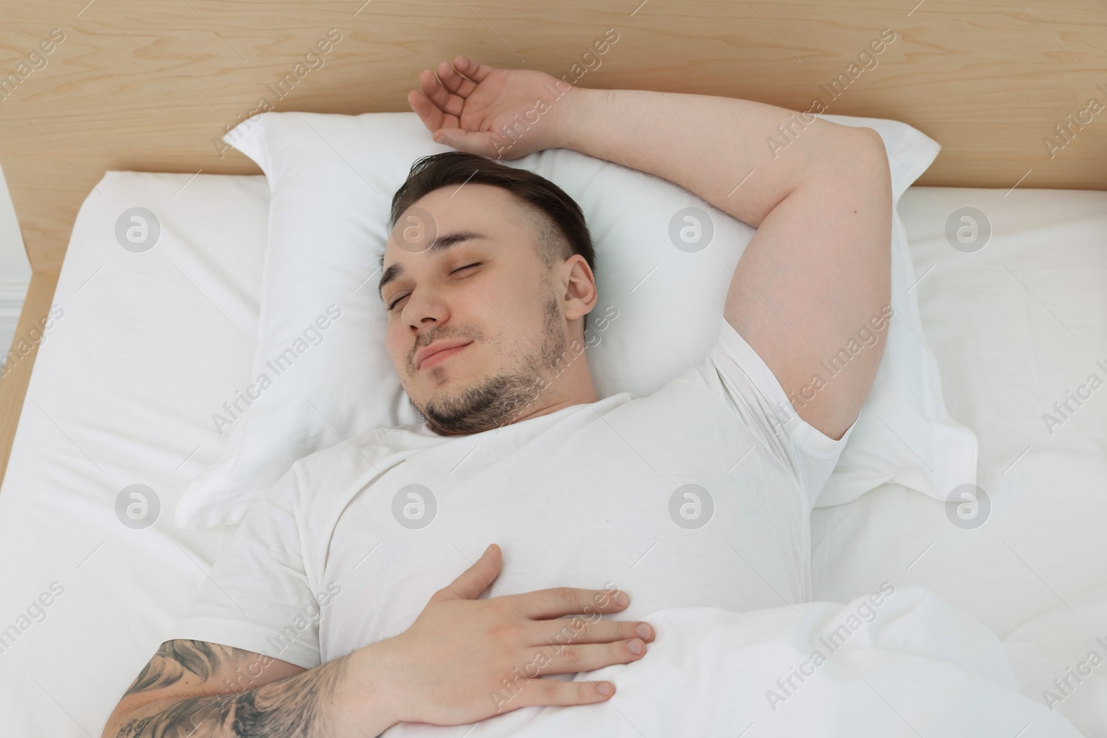 Photo of Bedtime. Handsome man sleeping in bed indoors, above view