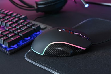 Photo of Computer mouse, mousepad and RGB keyboard on black background