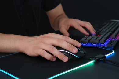 Photo of Gamer using modern wired computer mouse at black table, closeup