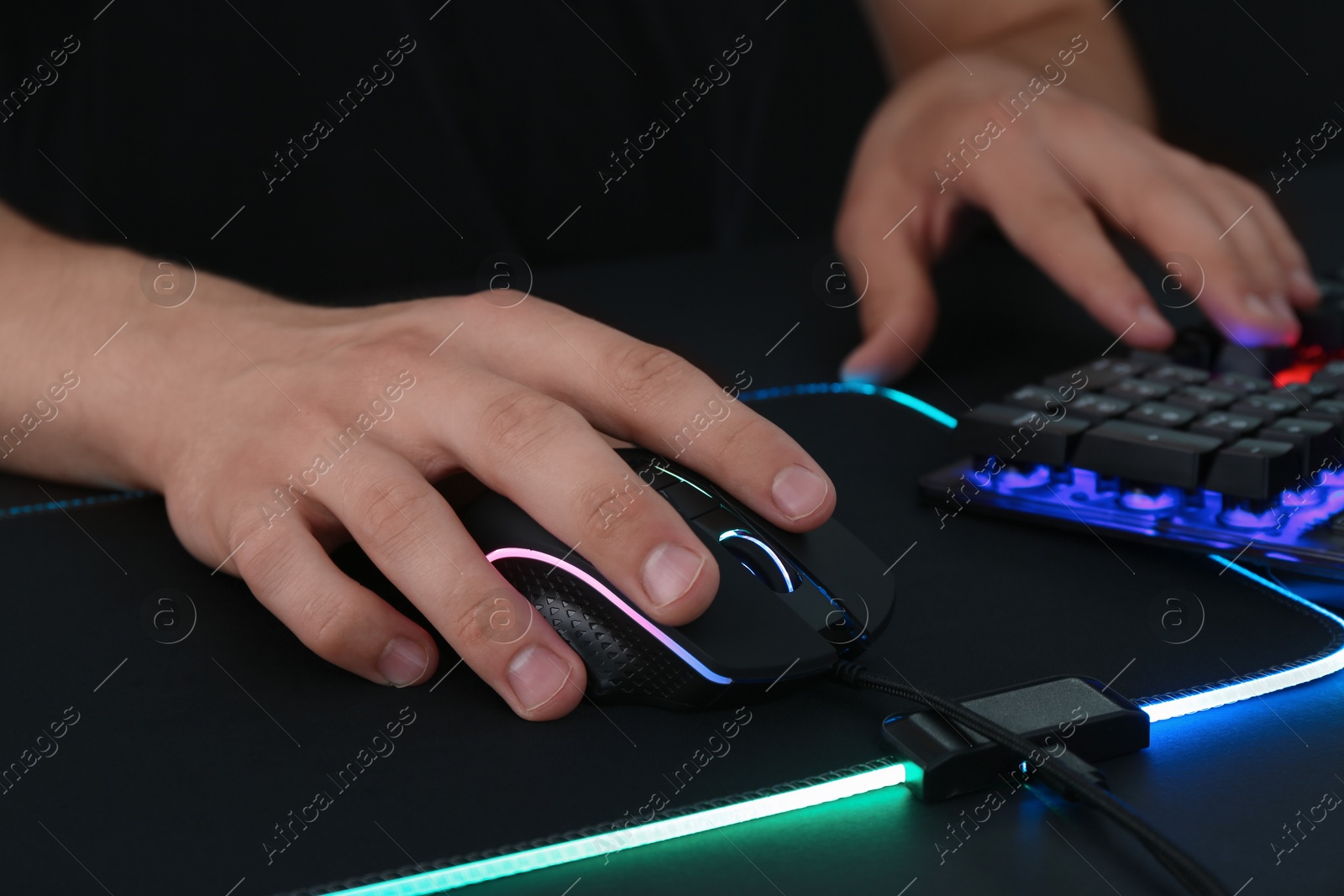 Photo of Gamer using modern wired computer mouse at black table, closeup