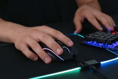 Photo of Gamer using modern wired computer mouse at black table, closeup