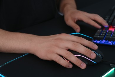 Photo of Gamer using modern wired computer mouse at black table, closeup