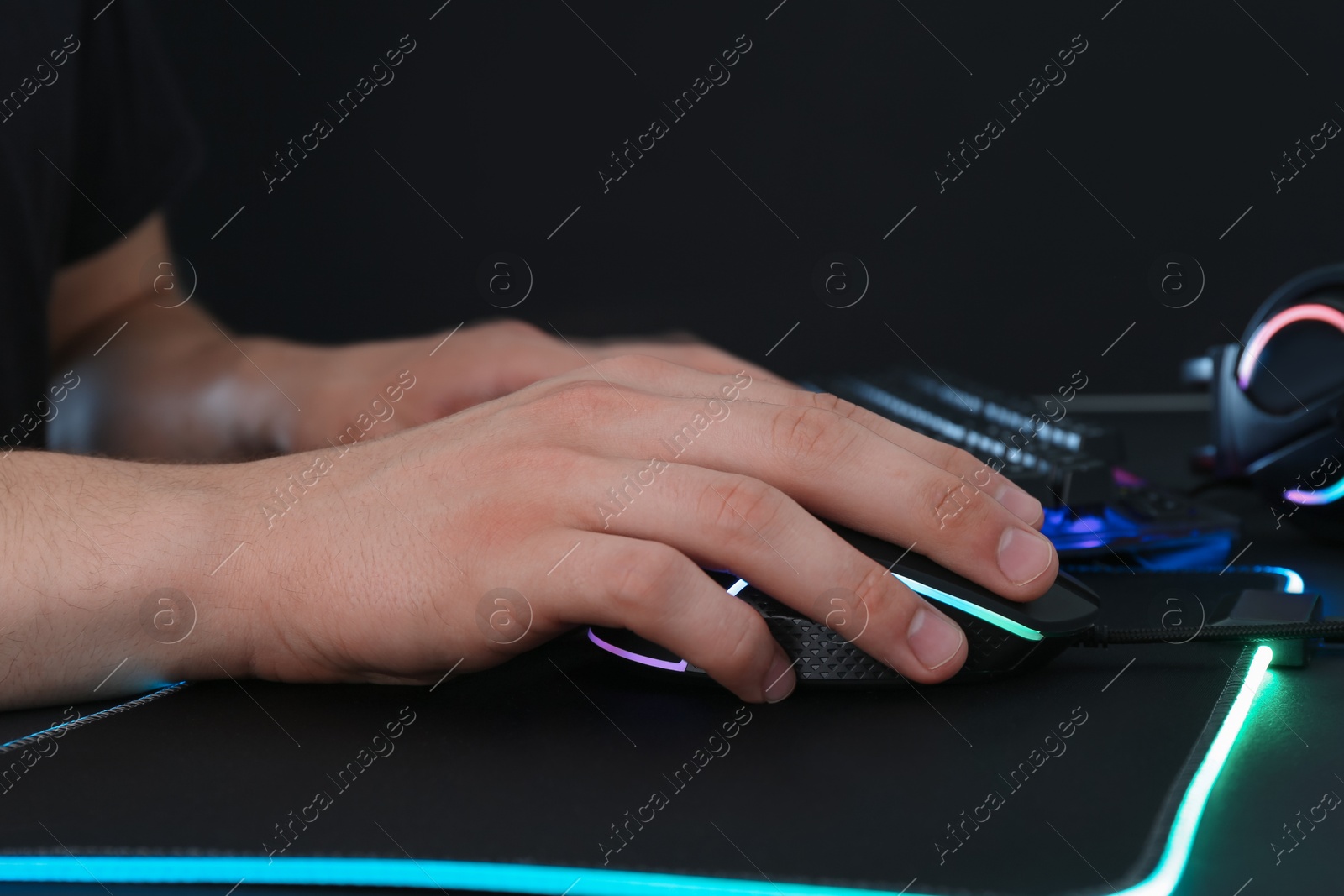 Photo of Gamer using modern wired computer mouse at black table, closeup