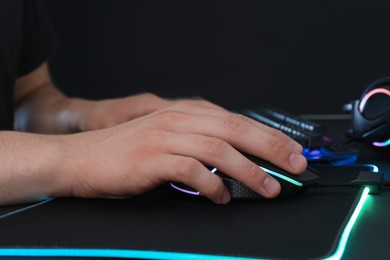 Photo of Gamer using modern wired computer mouse at black table, closeup