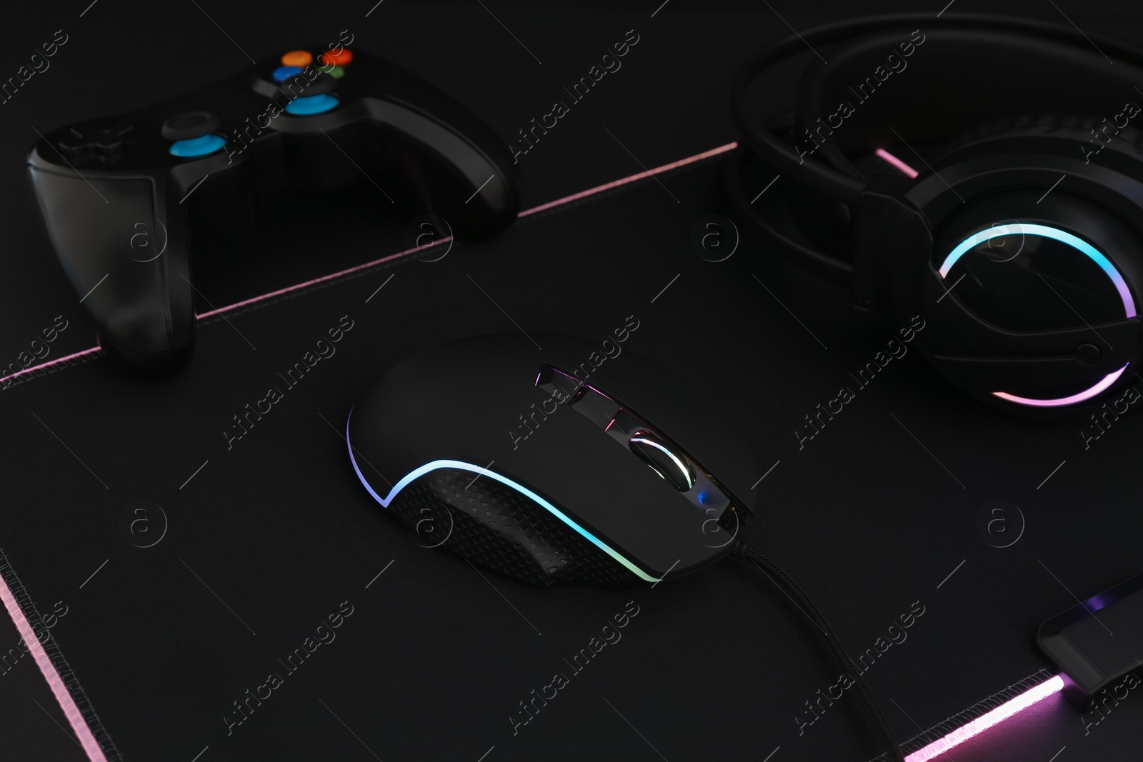 Photo of Computer mouse, headset and game controller on black background, closeup