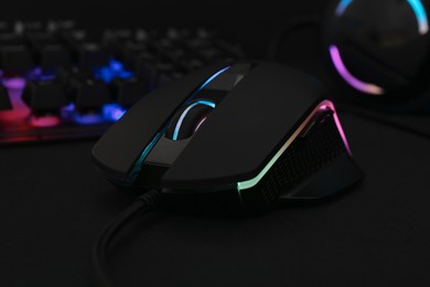 Computer mouse and RGB keyboard on black background, closeup