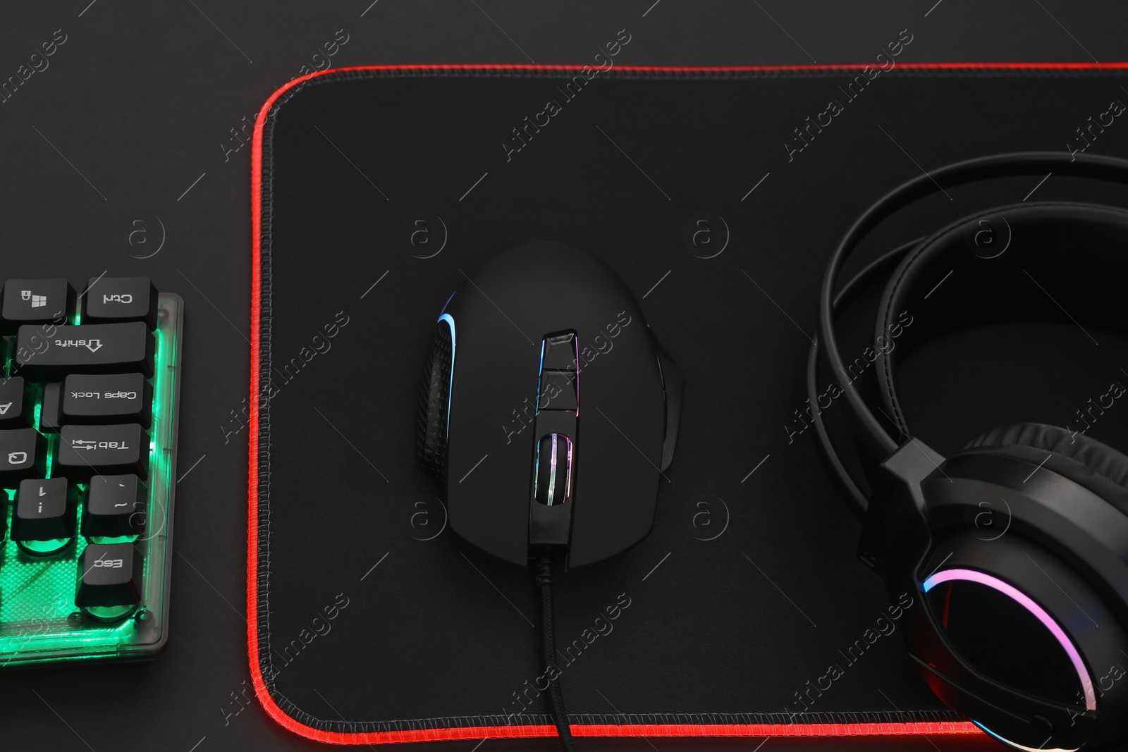 Photo of Computer mouse, headset and RGB keyboard on dark background, above view