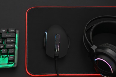 Computer mouse, headset and RGB keyboard on dark background, above view