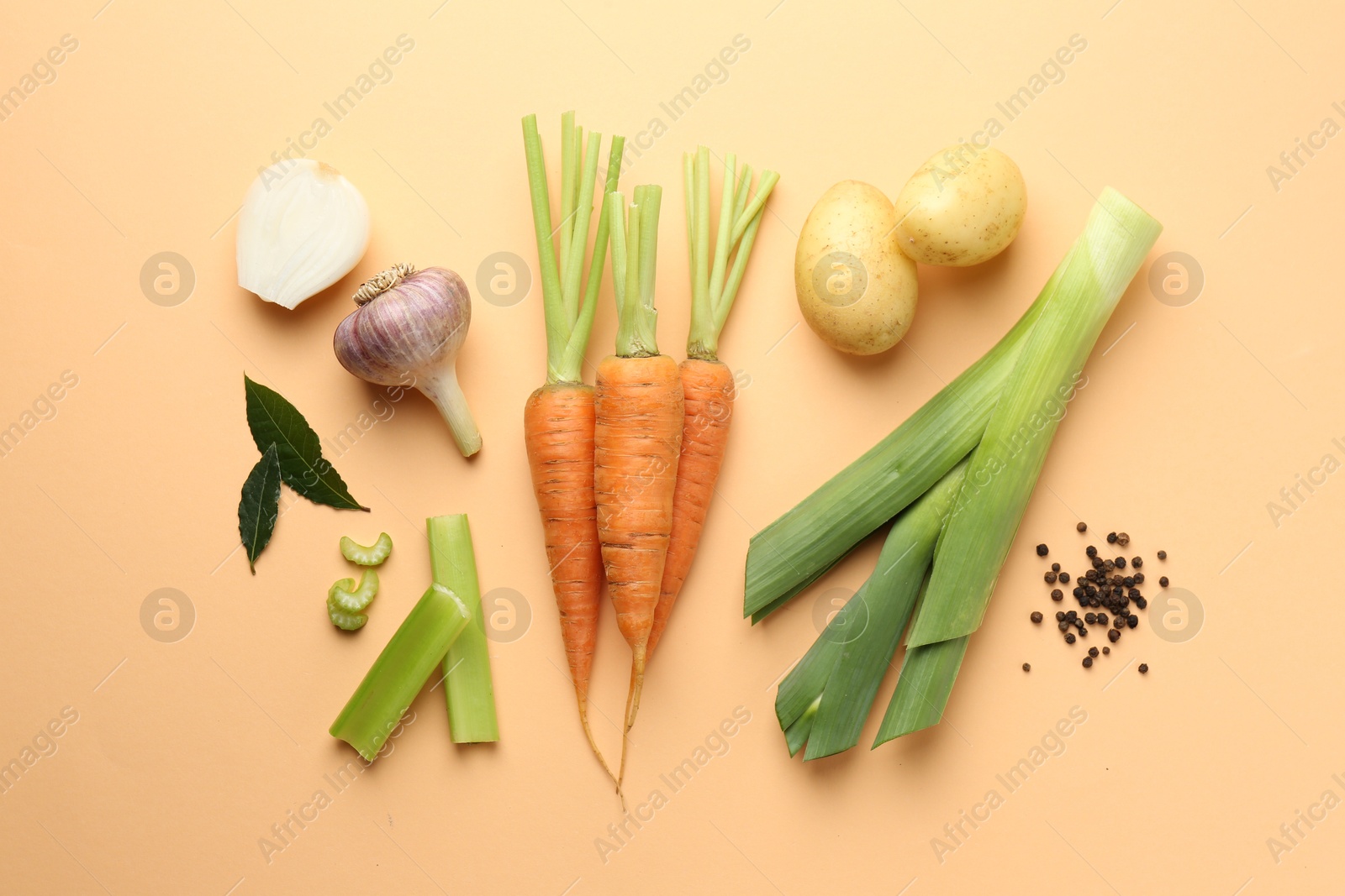 Photo of Fresh ripe carrots, vegetables and spices on pale orange background, flat lay