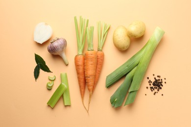 Photo of Fresh ripe carrots, vegetables and spices on pale orange background, flat lay