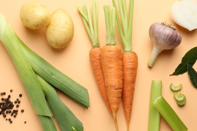 Fresh ripe carrots, vegetables and spices on pale orange background, flat lay