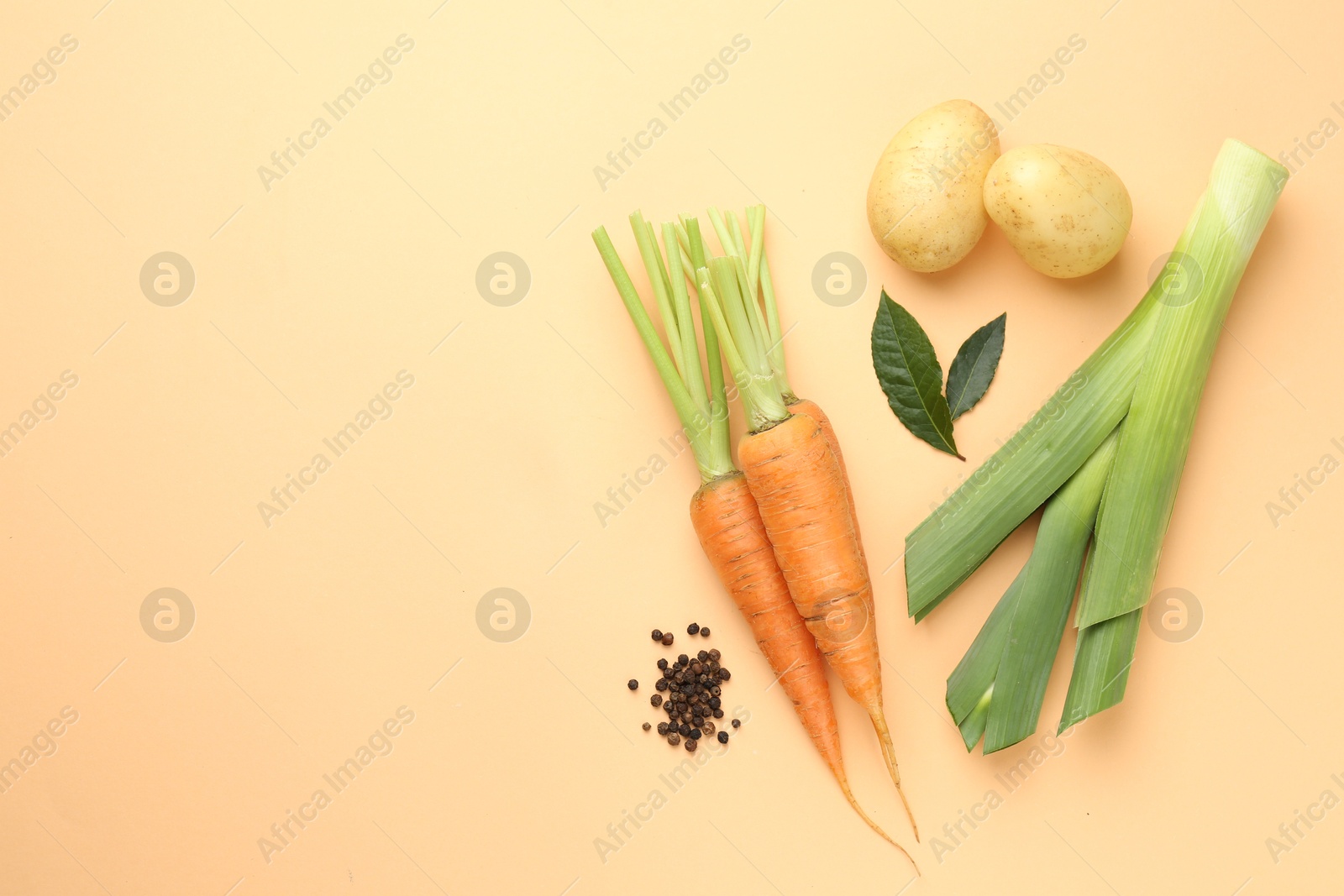 Photo of Fresh ripe carrots, vegetables and spices on pale orange background, flat lay. Space for text