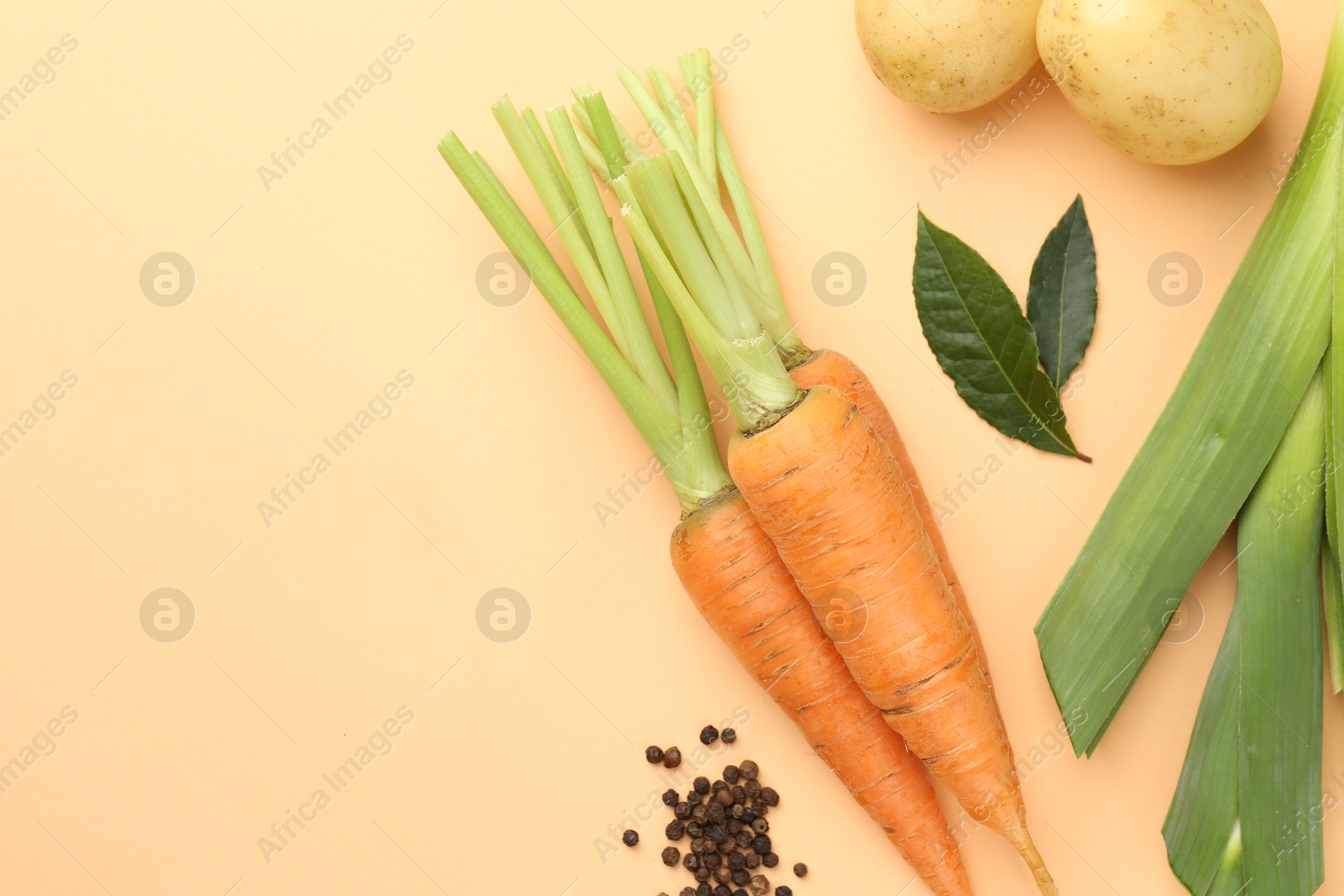 Photo of Fresh ripe carrots, vegetables and spices on pale orange background, flat lay. Space for text