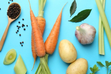 Photo of Fresh ripe carrots, vegetables, spices and spoon on light blue background, flat lay