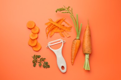 Photo of Fresh carrots, vegetable peeler and green leaf on orange background, flat lay