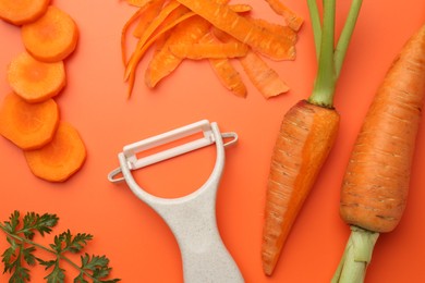 Photo of Fresh carrots, vegetable peeler and green leaf on orange background, flat lay