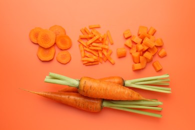 Photo of Whole and cut carrots on orange background, flat lay.