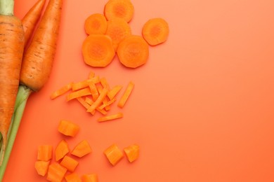 Whole and cut carrots on orange background, flat lay. Space for text