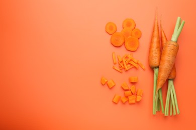 Photo of Whole and cut carrots on orange background, flat lay. Space for text