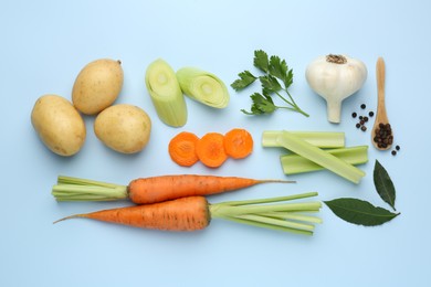 Photo of Fresh ripe carrots, vegetables, spices and spoon on light blue background, flat lay