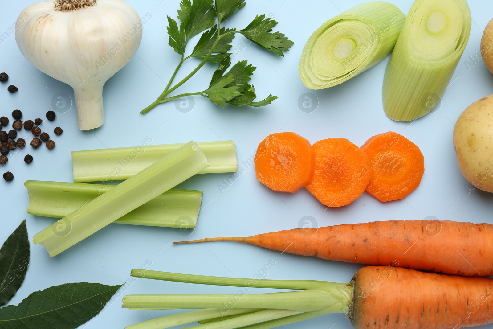 Photo of Fresh ripe carrots, vegetables and spices on light blue background, flat lay