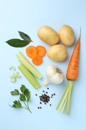 Photo of Fresh ripe carrots, vegetables and spices on light blue background, flat lay