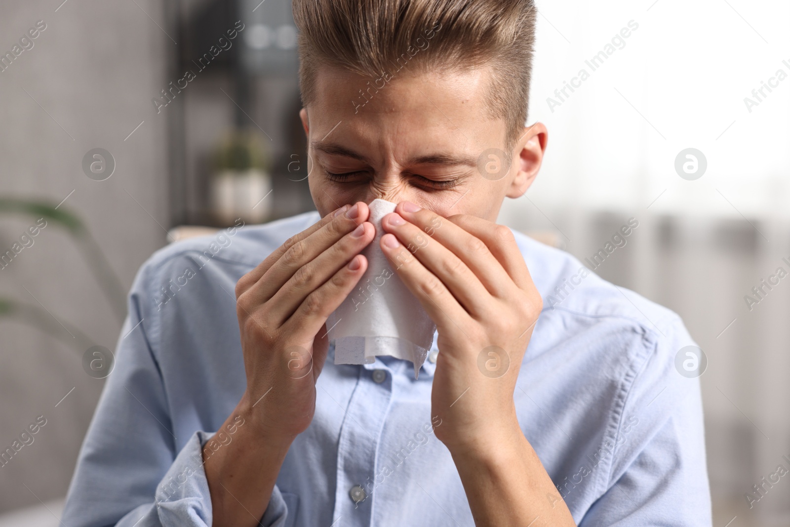 Photo of Young man with tissue suffering from sinusitis indoors