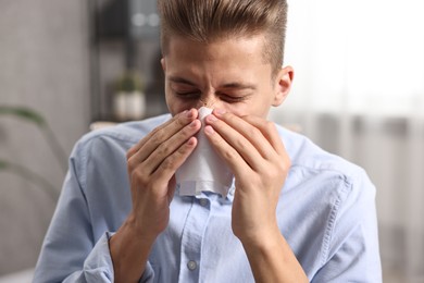 Photo of Young man with tissue suffering from sinusitis indoors