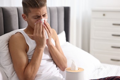 Photo of Young man with tissue suffering from sinusitis in bed at home