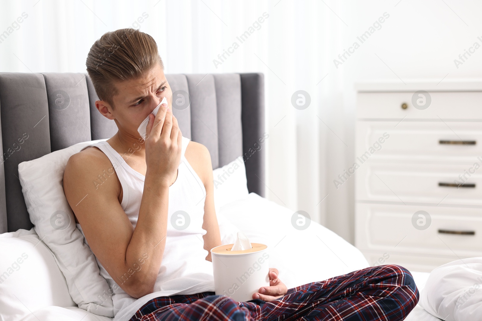 Photo of Young man with tissue suffering from sinusitis in bed at home