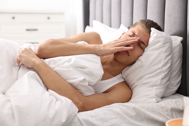 Photo of Young man suffering from sinusitis and lying in bed at home