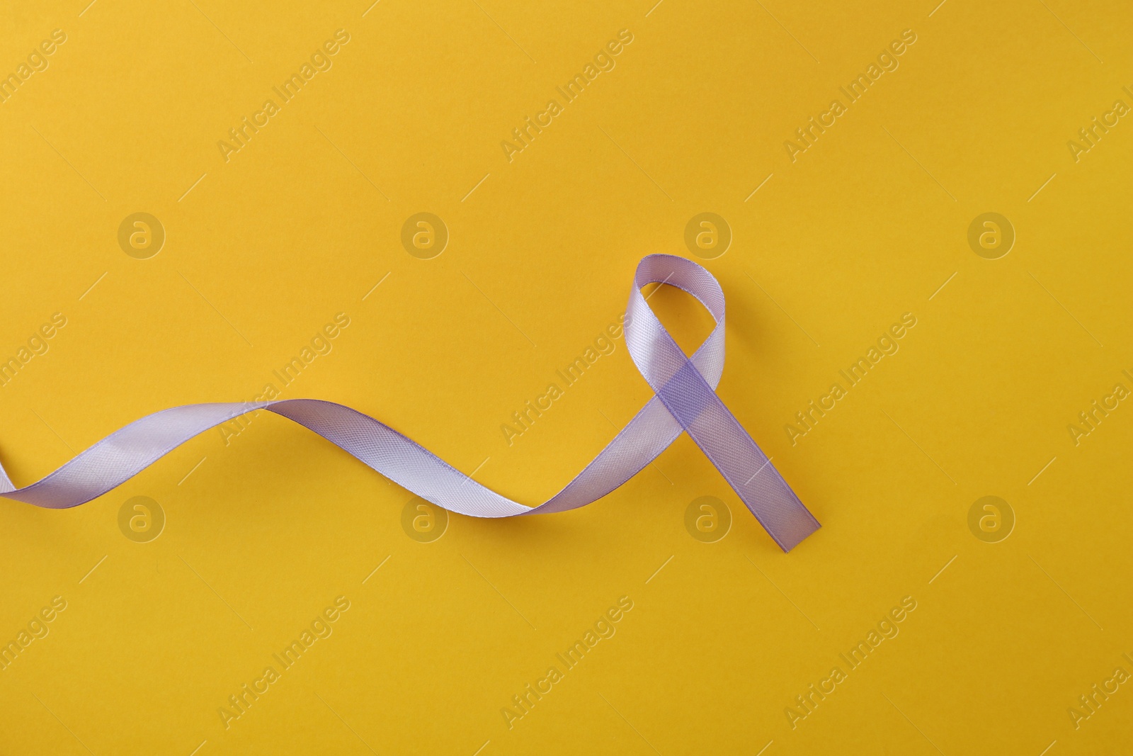 Photo of Violet awareness ribbon on orange background, top view