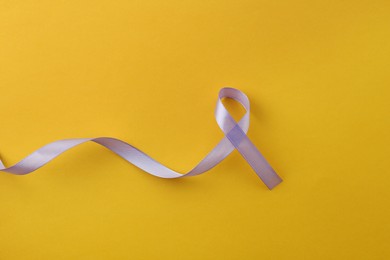 Photo of Violet awareness ribbon on orange background, top view