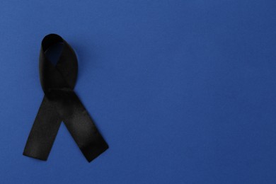 Photo of Black awareness ribbon on blue background, top view. Space for text