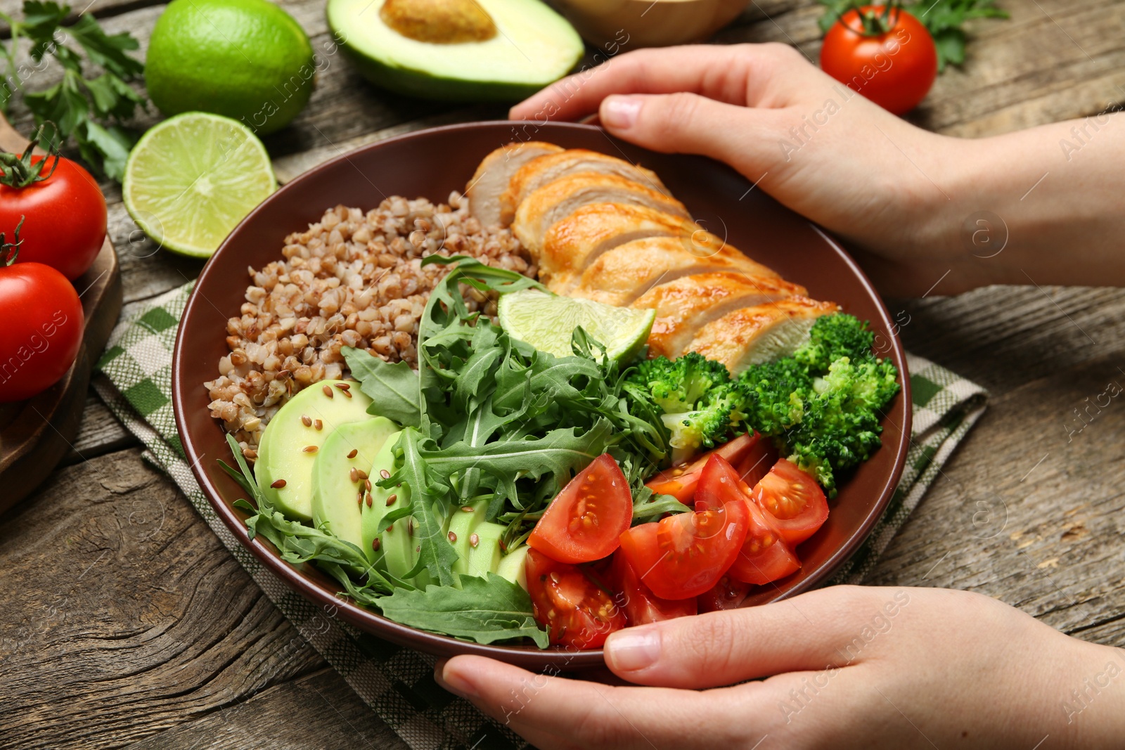 Photo of Healthy meal. Woman with tasty products in bowl at wooden table, closeup