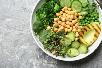 Healthy meal. Tasty vegetables and chickpeas in bowl on grey table, top view. Space for text