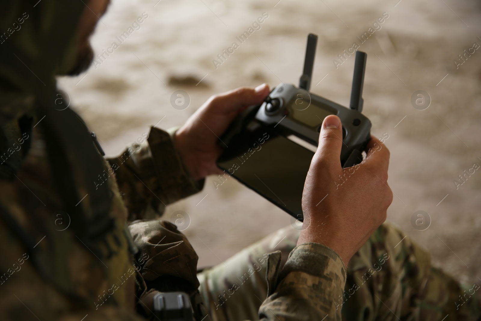 Photo of Military mission. Soldier in uniform with drone controller inside abandoned building, closeup