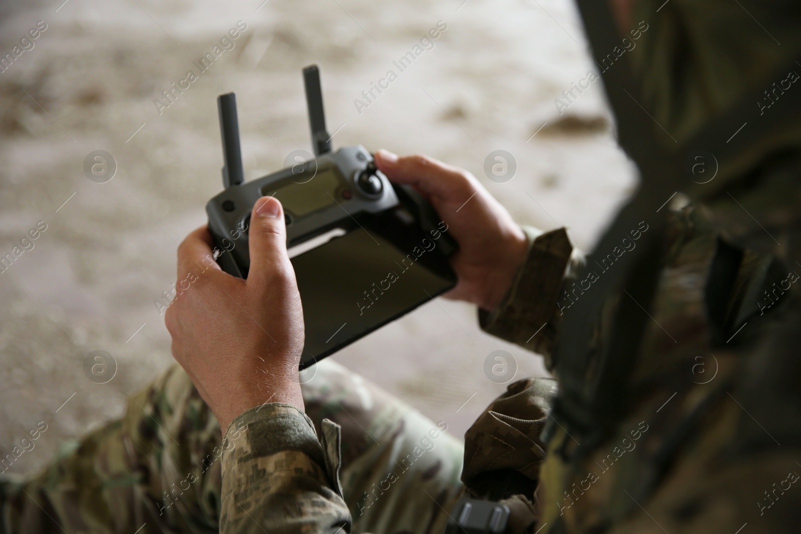 Photo of Military mission. Soldier in uniform with drone controller inside abandoned building, closeup