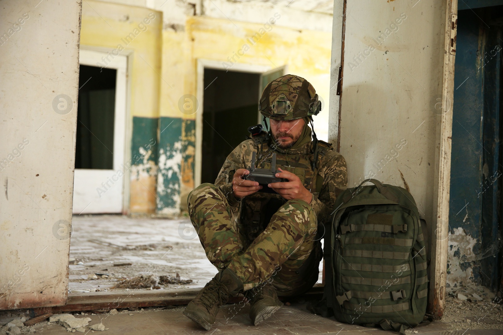 Photo of Military mission. Soldier in uniform with drone controller inside abandoned building