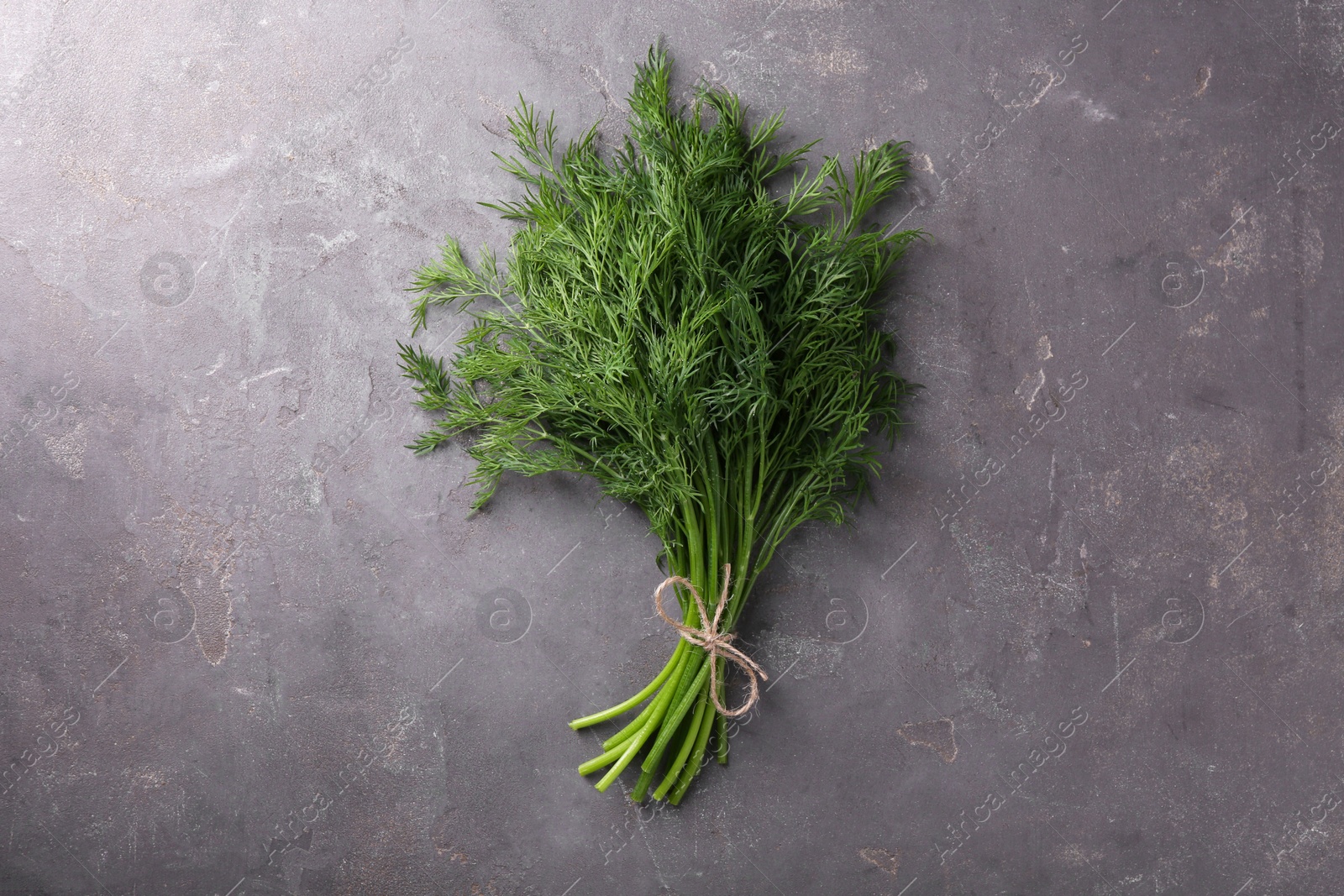 Photo of Bunch of fresh dill on grey textured table, top view