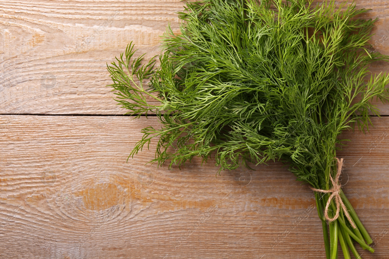 Photo of Bunch of fresh dill on wooden table, top view. Space for text