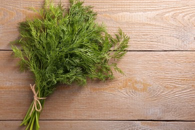 Photo of Bunch of fresh dill on wooden table, top view. Space for text