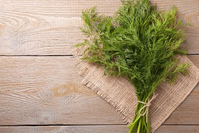 Photo of Bunch of fresh dill on wooden table, top view. Space for text