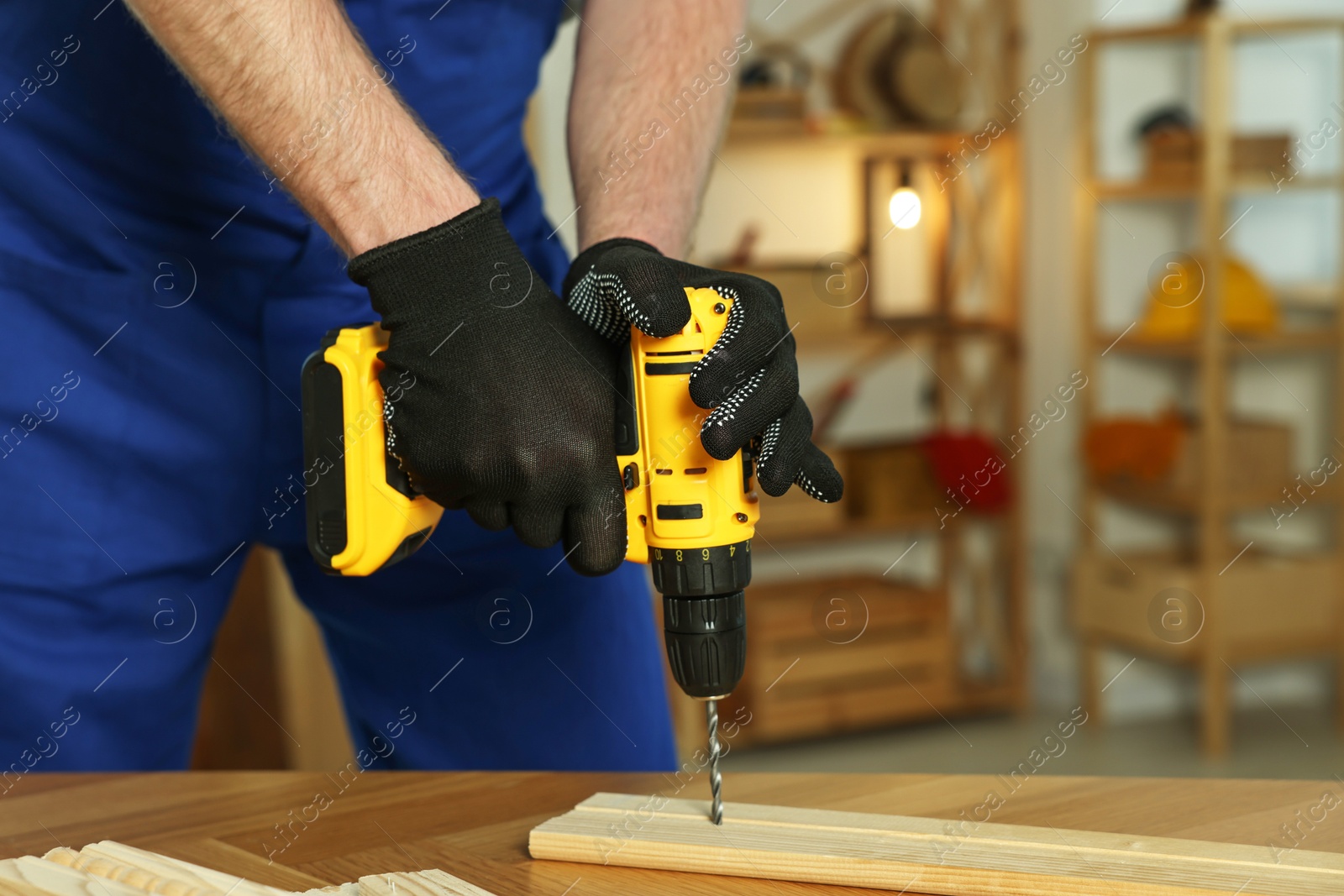 Photo of Craftsman working with drill at wooden table in workshop, closeup. Space for text