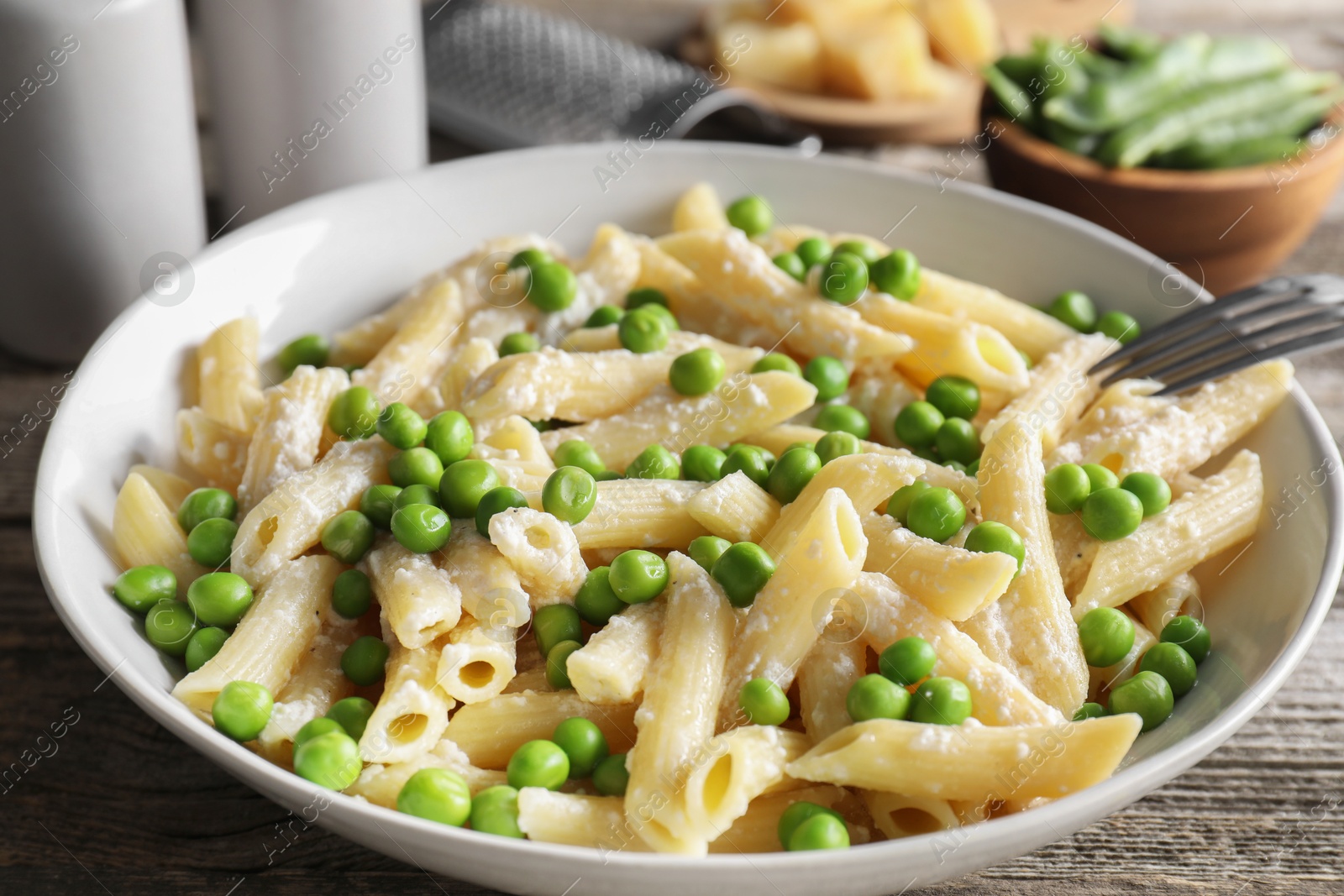 Photo of Delicious pasta with green peas and cheese on wooden table, closeup